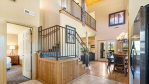 A spacious living area with a wooden staircase, a dining area, and a kitchen with a refrigerator. - Luxurious Walk-in Cabin with Private Screened Deck in the Heart of Branson (Branson)