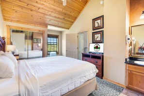 Relax in a traditional room with a large bed, wooden ceiling, and dresser, offering a view of the outdoors.