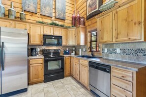 Kitchen features a refrigerator, microwave, oven, and dishwasher, along with a sink and tiled floor.