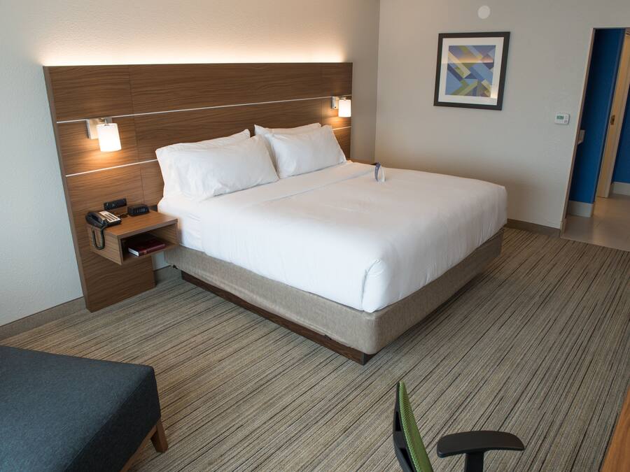 A hotel room with a large bed, bedside table with a phone, and a small seating area.