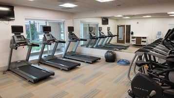 Ein Fitnessstudio mit Laufbändern, Gymbällen und einer Spiegelwand.