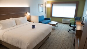 Une chambre d’hôtel avec un grand lit, un bureau, une chaise et une fenêtre donnant sur un beau paysage.