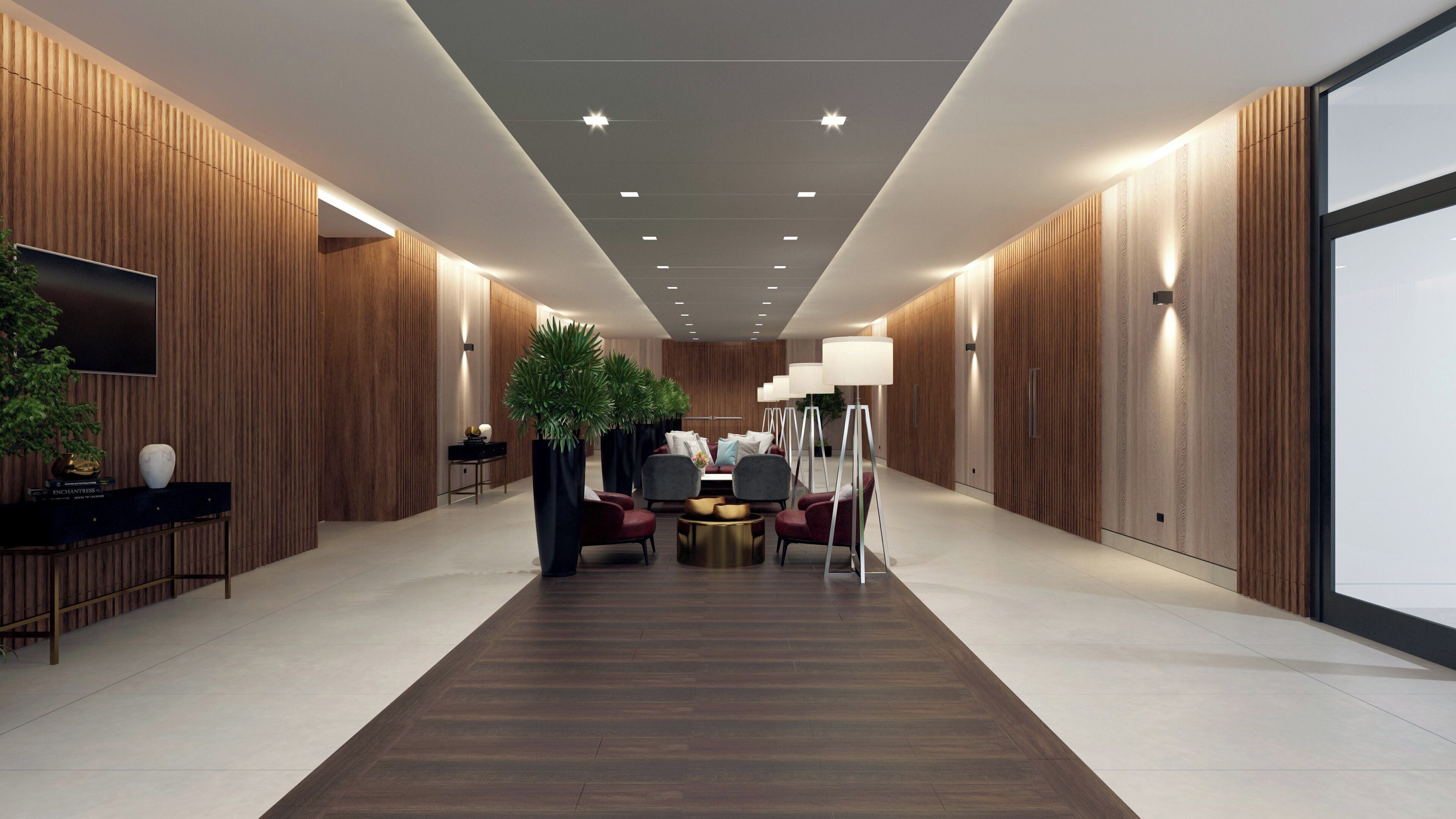 A modern lobby with a central seating area, wooden paneling on the walls, and a flat-screen TV mounted on the left.