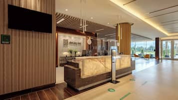 A hotel reception area with a marble counter, a television, and a sign indicating female restrooms.