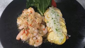 A plate with shrimp and a poached egg on a black plate.