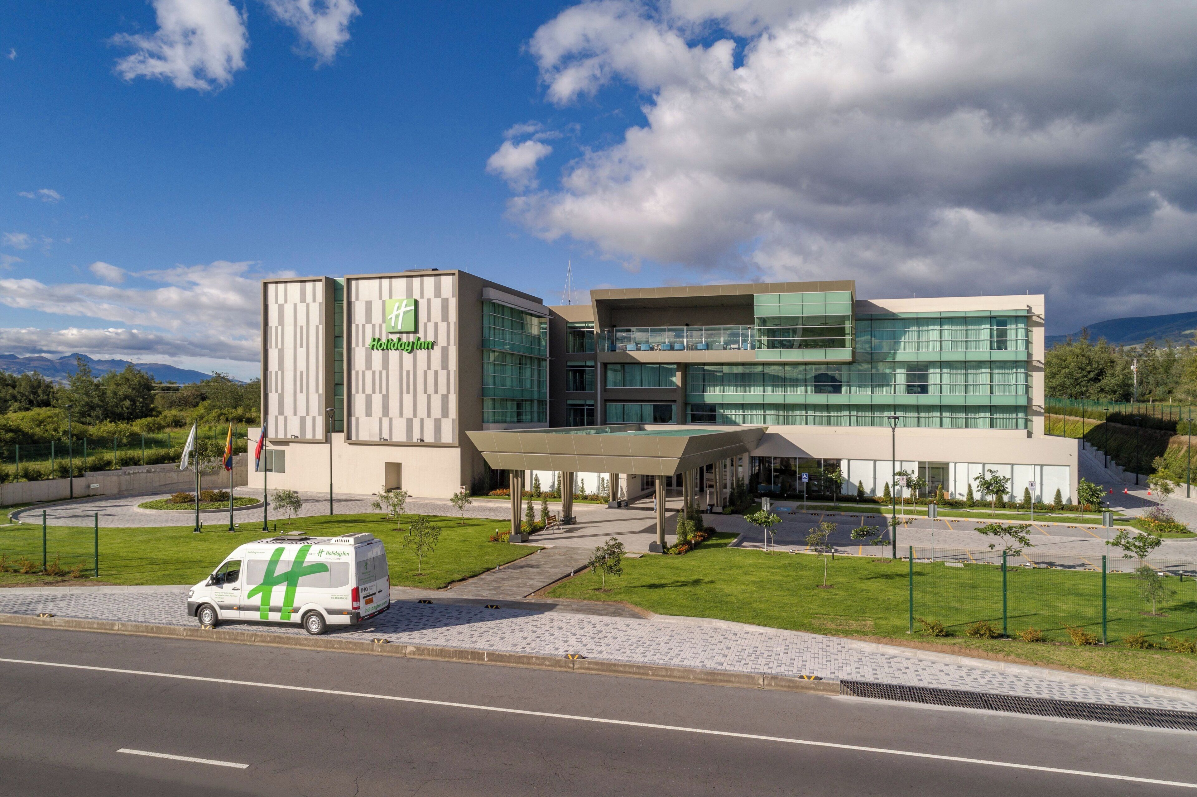 A Holiday Inn hotel with a modern design, featuring a covered entrance and a parking area.