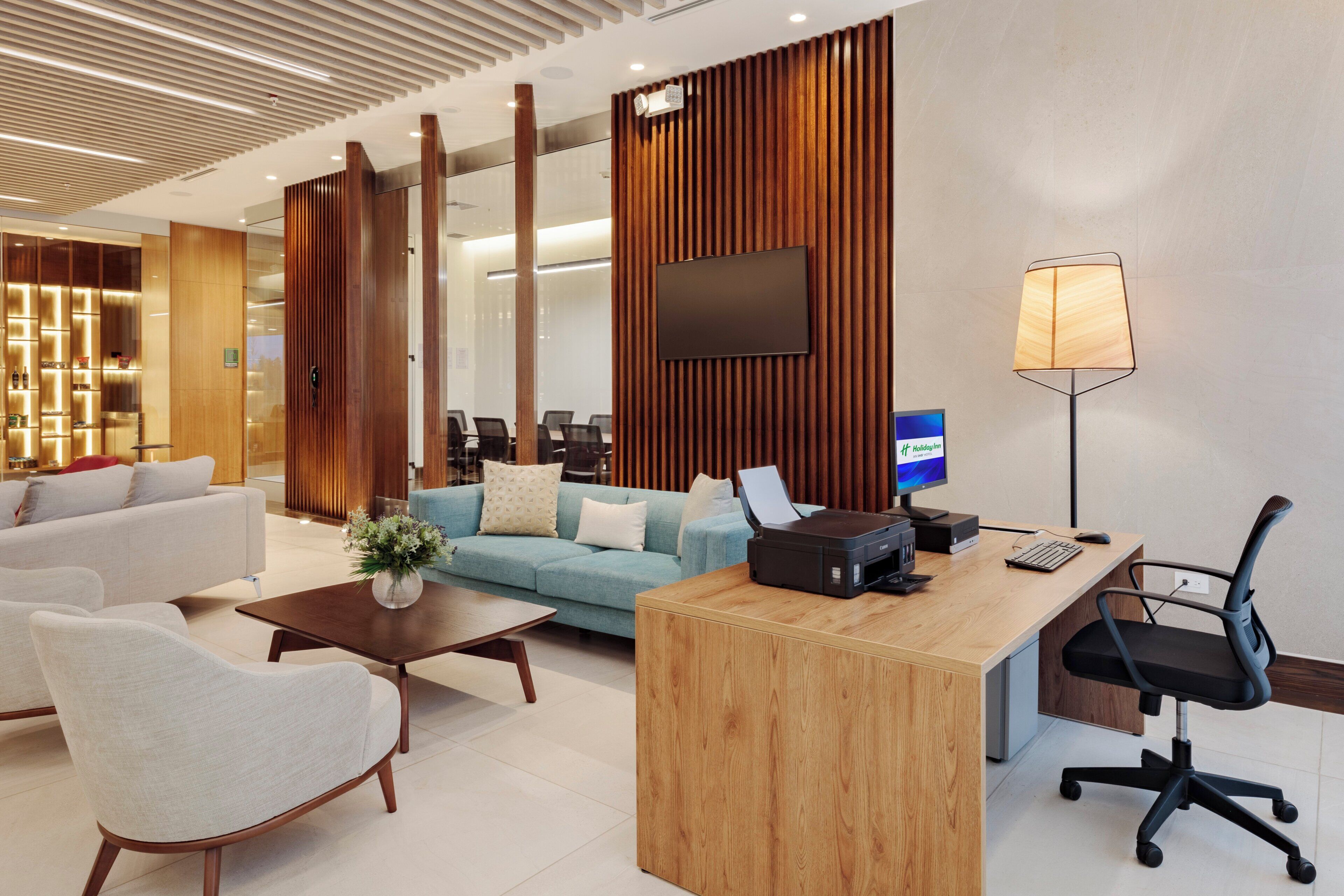 Un moderno vestíbulo de hotel con mostrador de recepción, zona de estar y una gran pantalla.