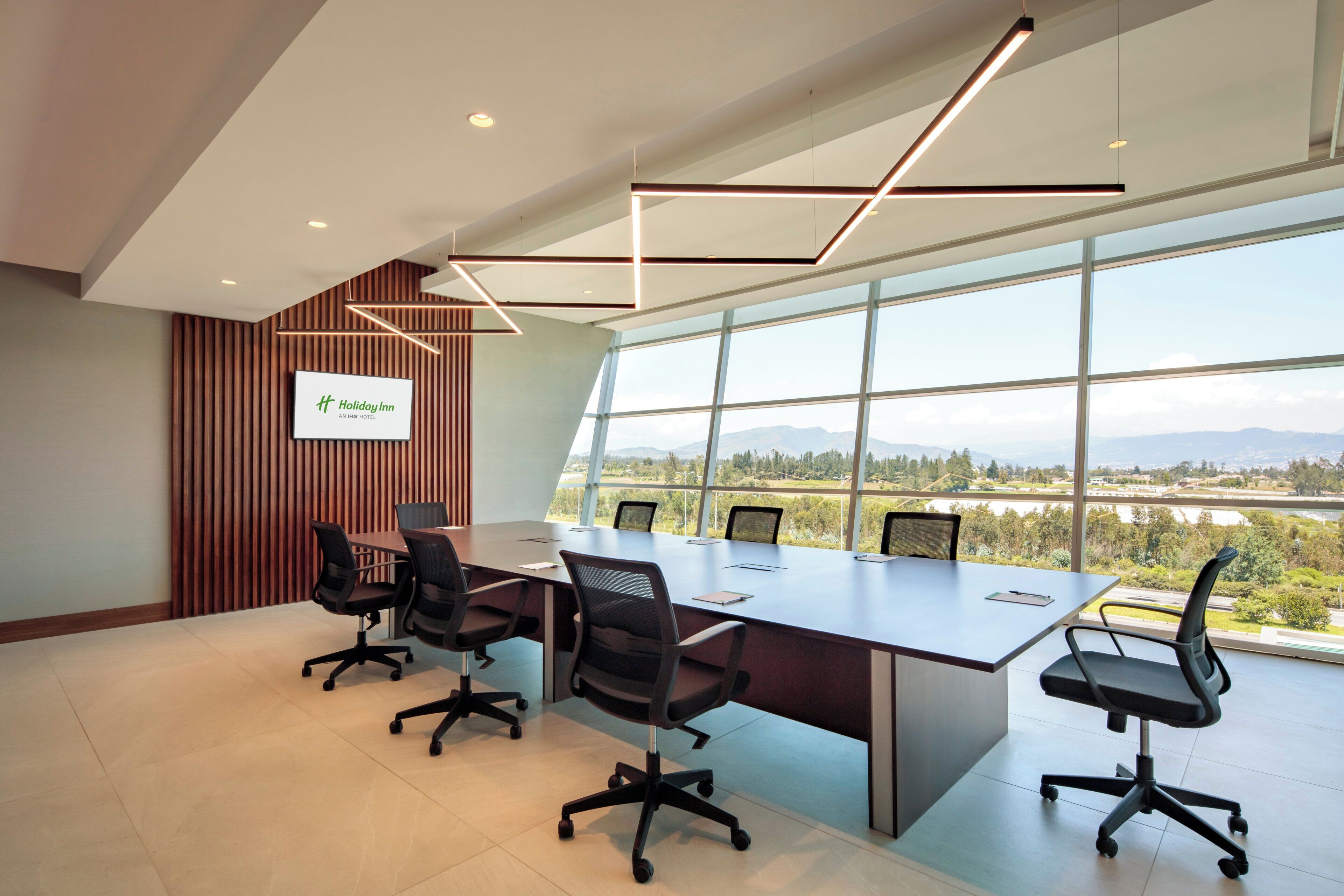 A conference room with a large table, chairs, and a view of the outdoors.