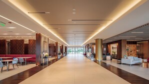 A spacious hotel corridor with a modern design, featuring a central walkway, seating areas on both sides, and a reception desk at the end. - Holiday Inn Quito Airport by IHG (Tababela)
