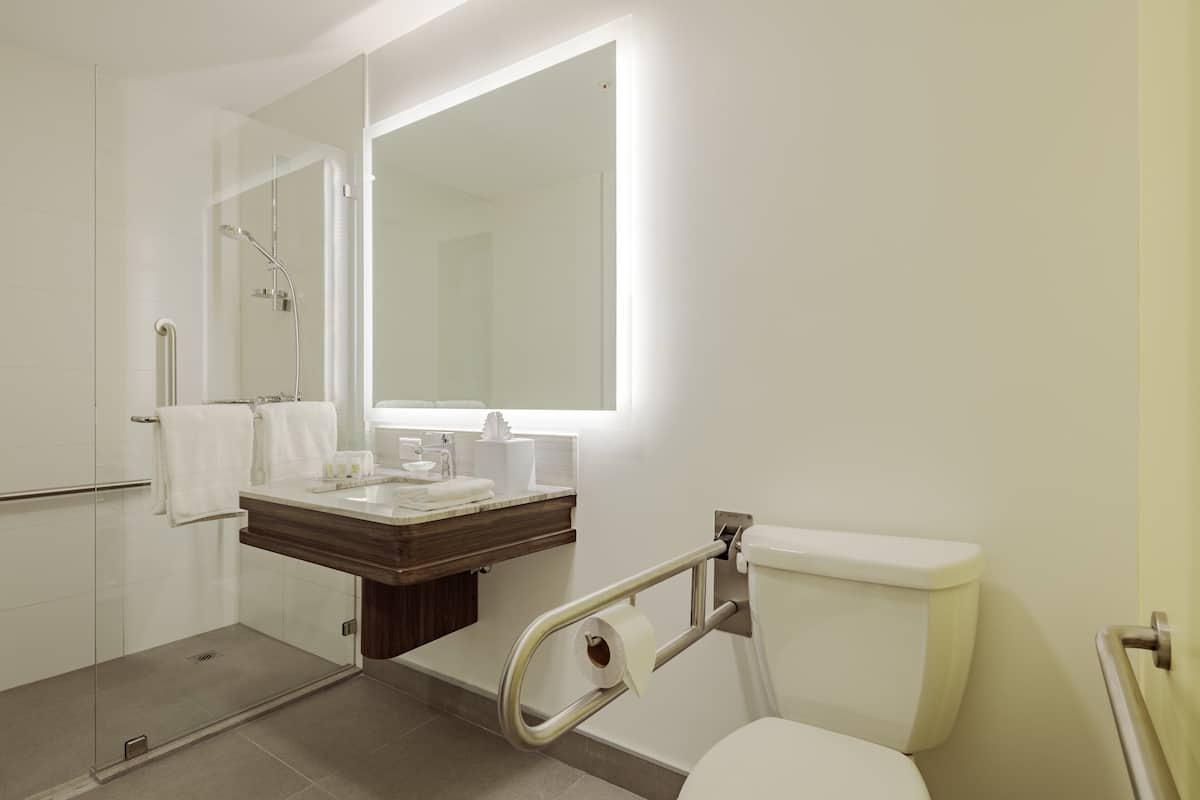 A modern bathroom with a glass shower enclosure, a white toilet, and a vanity with a mirror.