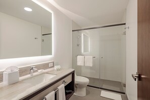 A modern bathroom with a large mirror, a sink, a toilet, and a glass-enclosed shower. - Holiday Inn Quito Airport by IHG (Tababela)