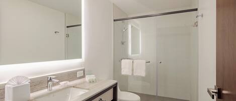 A modern bathroom with a glass-enclosed shower, a sink with a marble countertop, and a toilet.