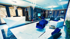 A modern lobby with a reception desk, seating area, and a large screen.