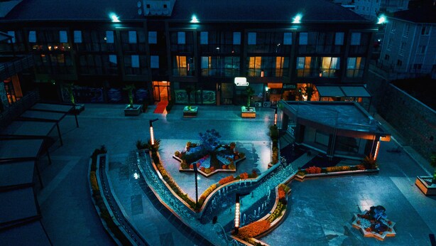 A courtyard with a fountain, seating areas, and a building with multiple windows and a sign that reads "GRILL".