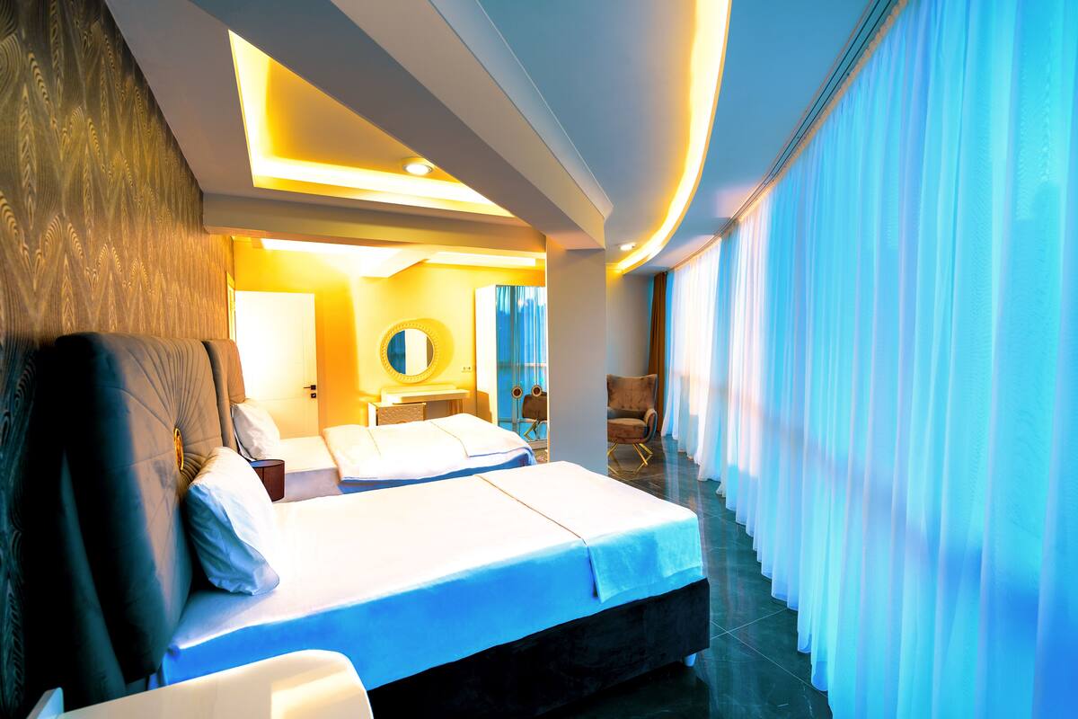A modern hotel room with a large bed, a sitting area, and a view of the outdoors.