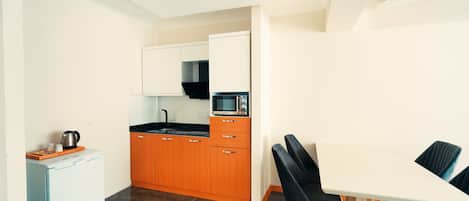 A compact kitchen with a refrigerator, microwave, and sink.