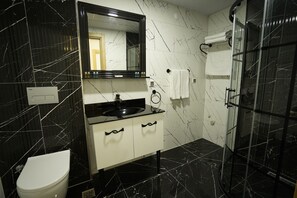 A modern bathroom with a black marble sink, white cabinet, and a glass shower enclosure. - Continent Luxury Suites Sakarya (Serdivan)
