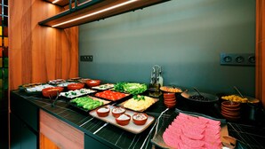 A buffet with various food items and a kitchen area with appliances.