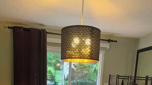 A dining table set with a decorative centerpiece, a hanging light fixture, and a view of the outdoors. - Family Launch Pad (Asheville)