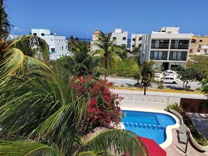 A residential area with a swimming pool, palm trees, and modern buildings.