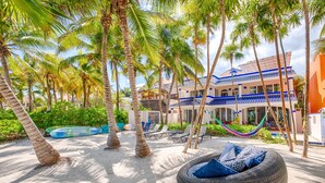 Un resort con palmeras, piscina y un edificio con detalles azules.