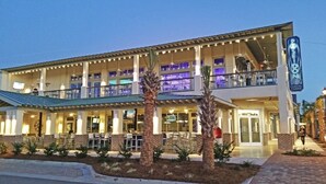 A coastal restaurant with outdoor seating, a covered patio, and a neon sign.