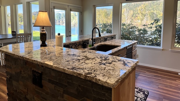 Una cocina con una isla de piedra, vistas a un lago y un cartel que dice "The Best Place To Be Is Together".