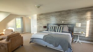 A bedroom with a large bed, a chair, a nightstand, and a lamp. - Fundy Sunset Cottage, Oceanfront Tranquility!! (granville ferry)