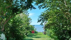 A pathway leading to a red structure with a view of the sea. - Fundy Sunset Cottage, Oceanfront Tranquility!! (granville ferry)