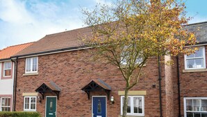 A brick building with a blue door and windows, surrounded by well-maintained hedges and a tree. - 2 bedroom accommodation in Filey (Filey)