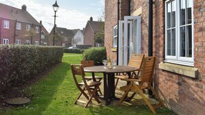 A brick house with a patio table and chairs, a door, and a window. - 2 bedroom accommodation in Filey (Filey)