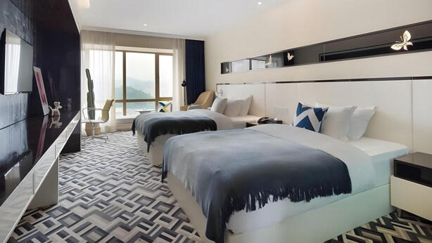 A modern hotel room with two beds, a large window with a city view, a flat-screen TV, and a patterned floor. - Greentree Alliance Hotel Guiyang Huaguo Community Central Business Zone (Guiyang)