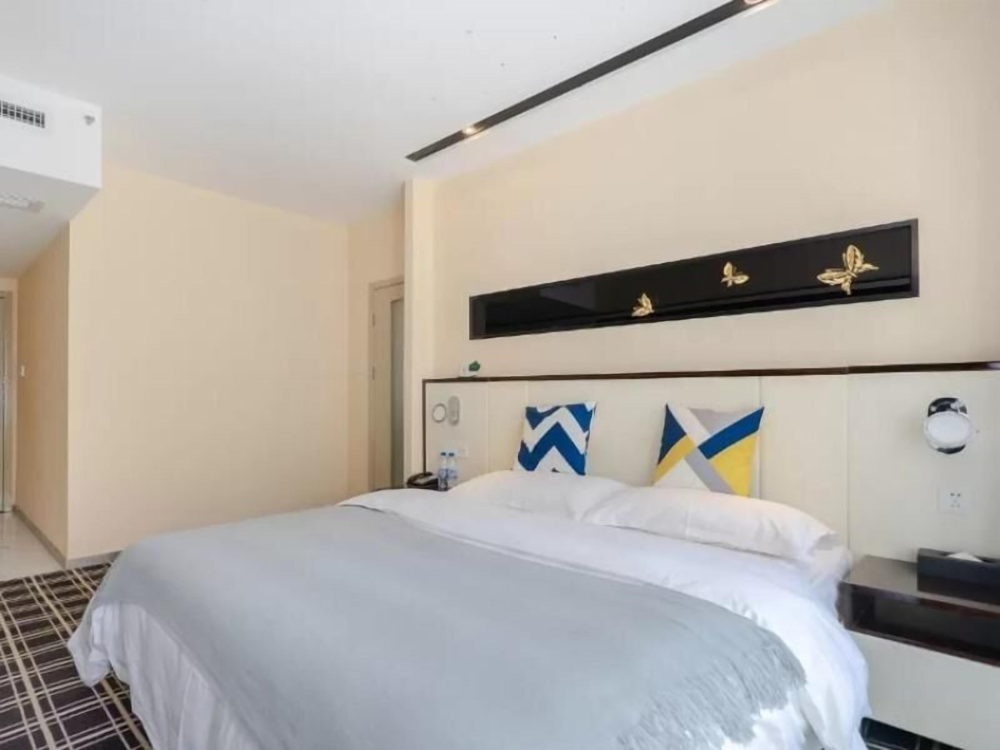 Quarto de hotel com cama, mesa de cabeceira, televisão na parede e unidade de ar condicionado no teto.