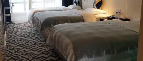 Una habitación de hotel con dos camas, alfombra estampada y una mesita de noche con lámpara.