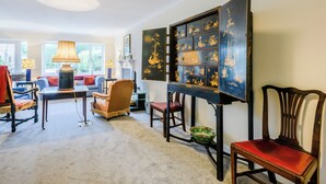 En hyggelig stue med et stort, detaljeret skab, en behagelig sofa og et spisebord.