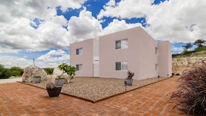 Un edifici modern de dues plantes amb teulada plana i façana de color rosa clar.