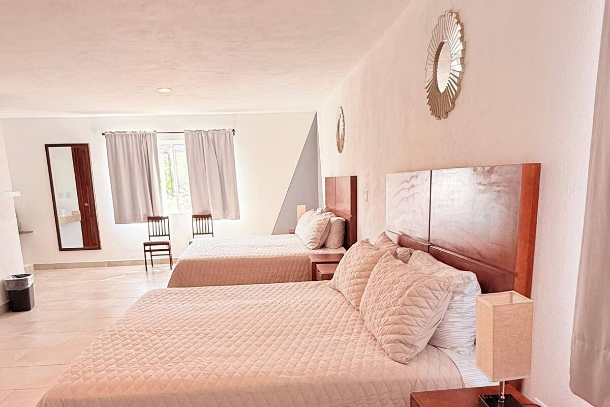 Une chambre spacieuse avec un grand lit, une table de chevet avec une lampe et un fauteuil.