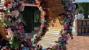 Arranjament floral amb forma de cor, amb una arcada de fusta, damunt d'un camí de maó.