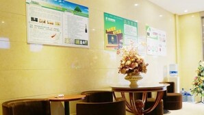 A lobby with a round table, two chairs, and a floral centerpiece. There are informational posters on the wall and a water dispenser.