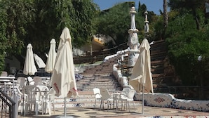 Sitzbereich im Freien mit Sonnenschirmen, eine geflieste Treppe und eine Palme.