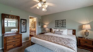 A bedroom with a large bed, a dresser, a vanity, and a ceiling fan. - 2 Bedroom, 2 Bathroom Walk-in Golf Condo with Covered Balcony, Indoor Pool Access (Branson)