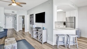 A modern kitchen with white cabinets, a built-in refrigerator, and a bar area with stools.