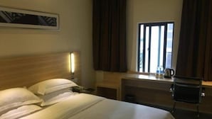 A hotel room with a large bed, a desk with a chair, a window with curtains, and a wall-mounted lamp. - City Comfort Inn Guangzhou Tiyu West Road Metro Station (Guangzhou)