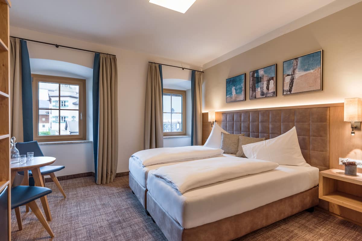 Habitación de hotel con una cama grande, dos mesitas de noche, un escritorio con silla y una ventana con cortinas.