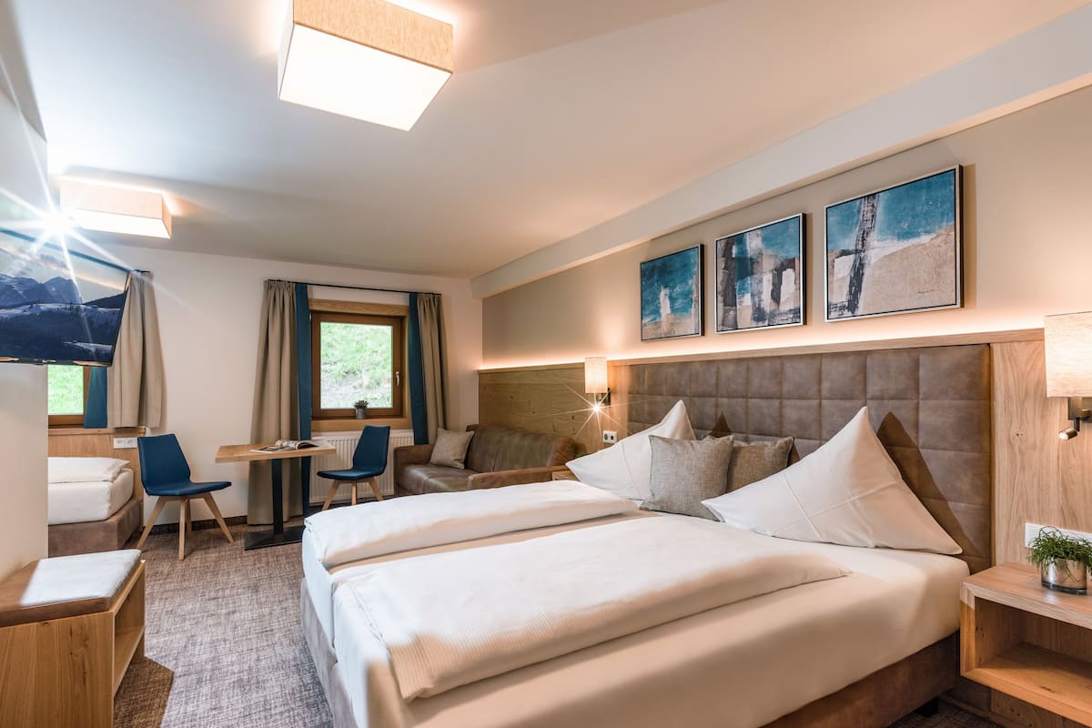 Una habitación de hotel con una cama grande, un escritorio, una silla y una ventana con cortinas.