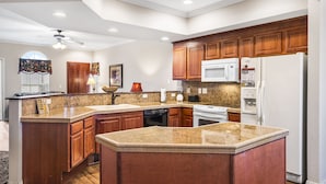A kitchen with granite countertops, wooden cabinets, a microwave, a refrigerator, and a dishwasher. - Branson 2BR • Roll-In Shower • Near Aquarium, Tanger & Dining (Branson)