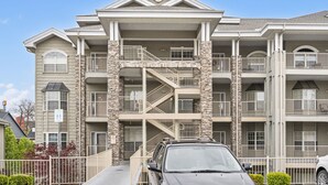 A multi-story building with a central staircase, balconies, and a car parked in front. - Branson 2BR • Roll-In Shower • Near Aquarium, Tanger & Dining (Branson)