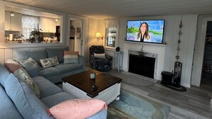 Een moderne woonkamer met een grijze bank, een salontafel, een televisie en een open haard.