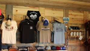 Una tienda con paredes de madera que exhibe sombreros y camisetas.