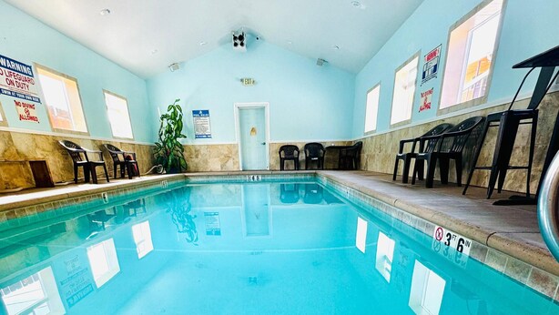 An indoor swimming pool with clear water, marked depth lines, and a lifeguard on duty sign. - Americas Best Value Inn Salmon (Salmon)